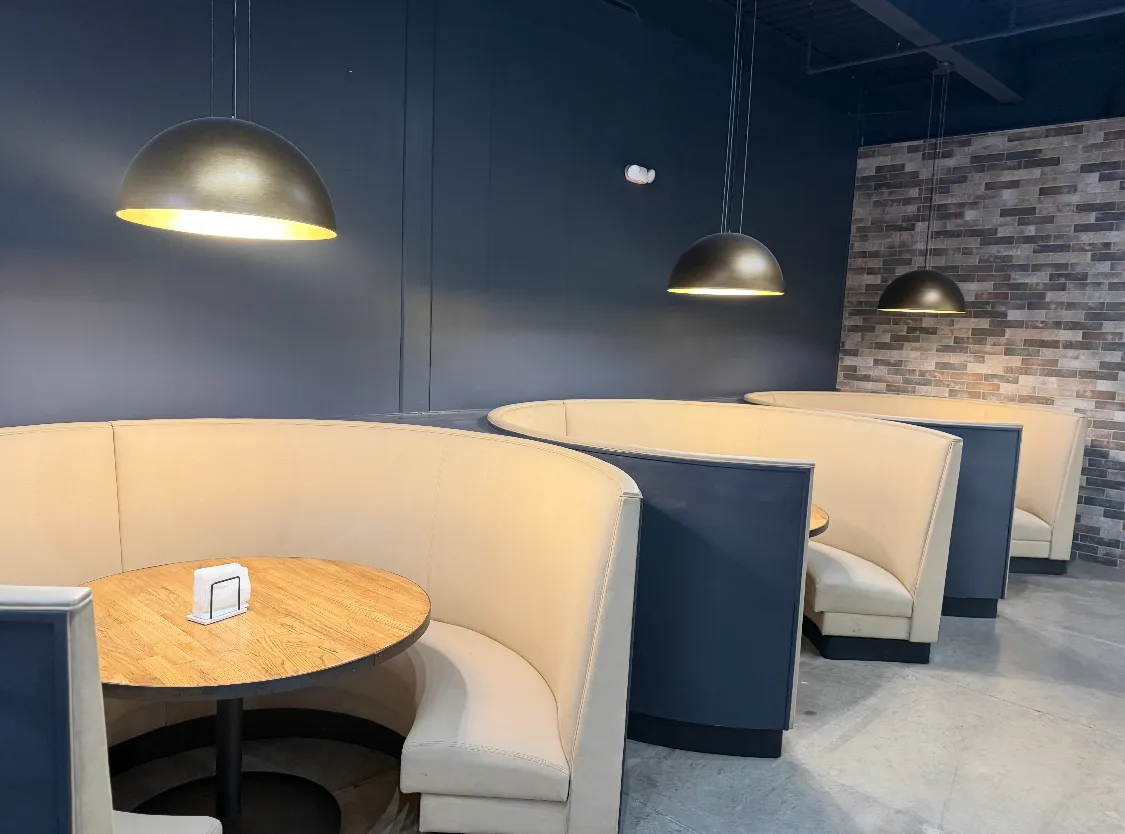 Curved cream booths under brass pendant lights