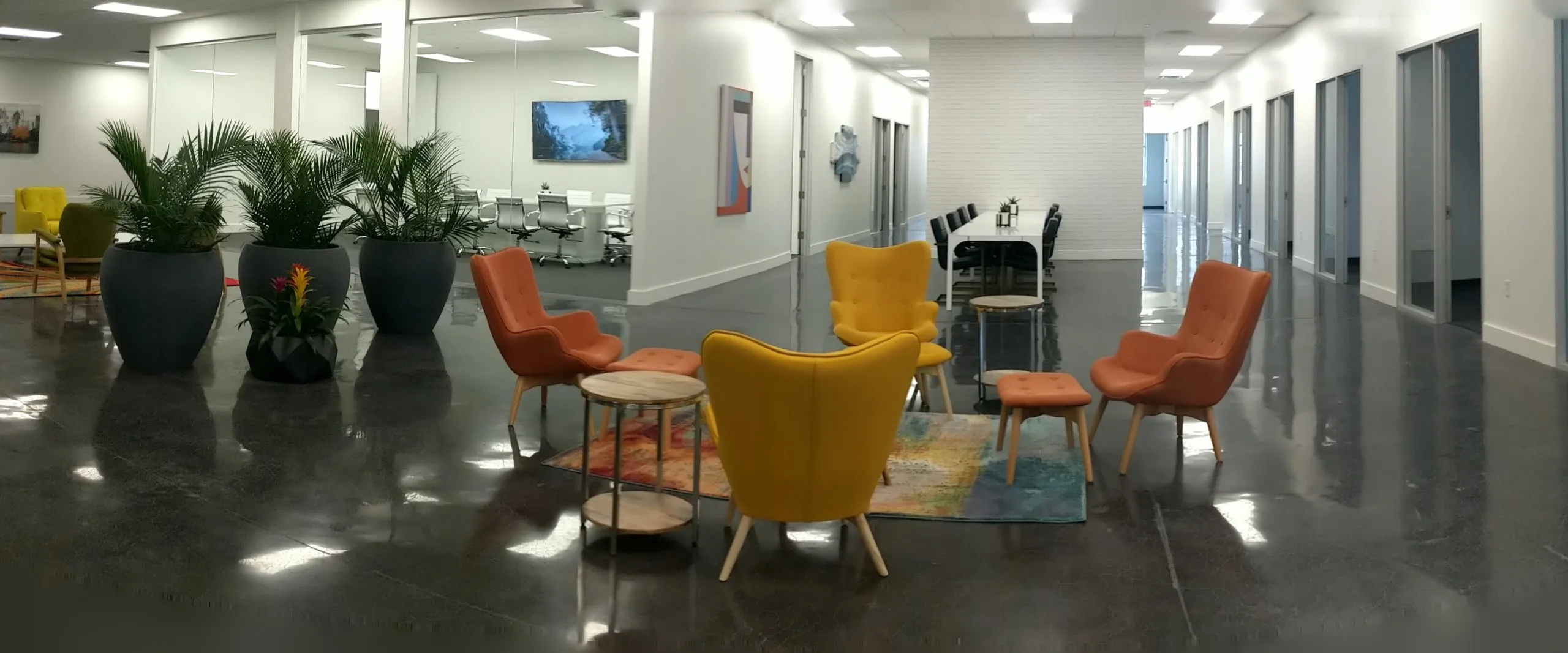 The open floor at Areté WorkSpaces: a long, bright room with plants, lounge chairs and glass-walled offices